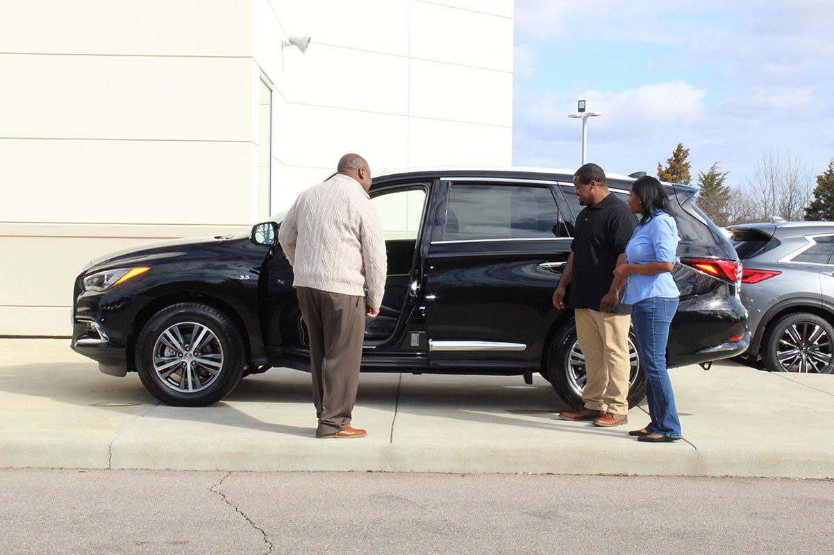 Three people stand by an INFINITI SUV